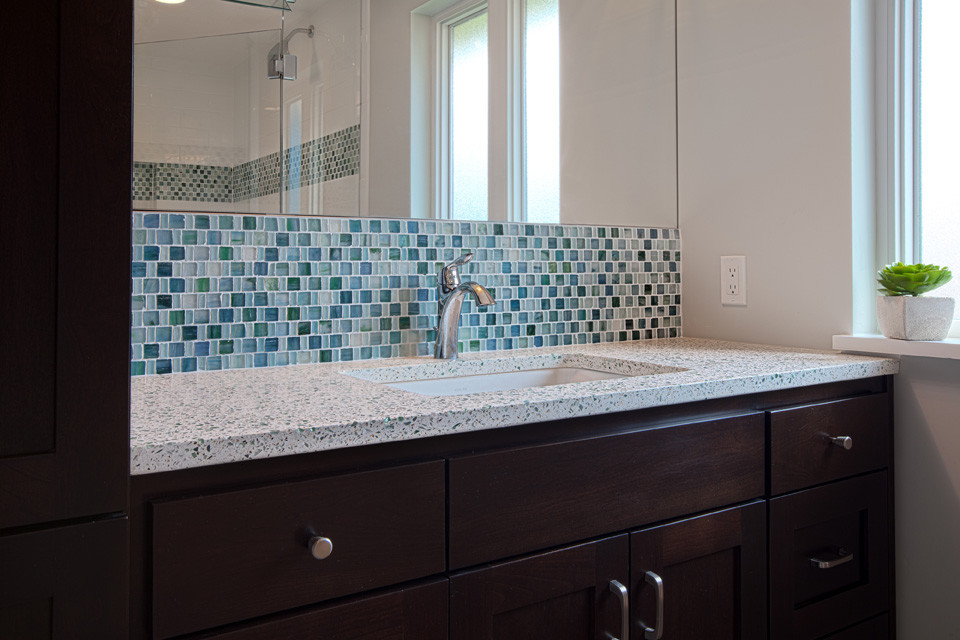 Immagine di una stanza da bagno chic di medie dimensioni con lavabo sottopiano, ante in stile shaker, ante in legno bruno, top in vetro riciclato, WC monopezzo, piastrelle blu, piastrelle di vetro, pareti beige e pavimento in gres porcellanato