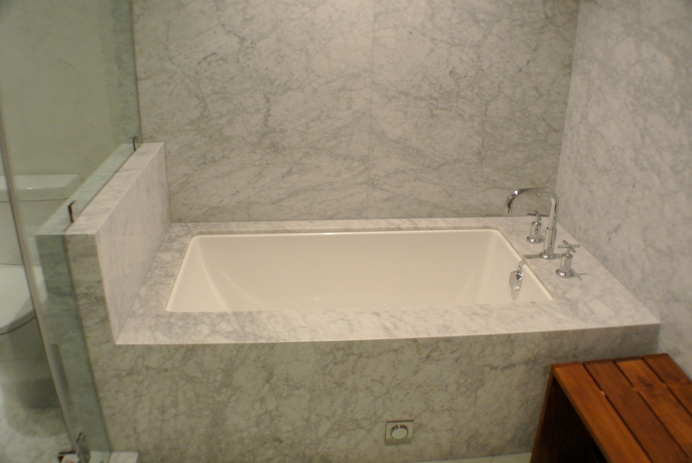 Exemple d'une salle de bain tendance avec un lavabo encastré, une baignoire encastrée, un combiné douche/baignoire, WC séparés, un placard en trompe-l'oeil, des portes de placard marrons, un plan de toilette en marbre et un carrelage gris.