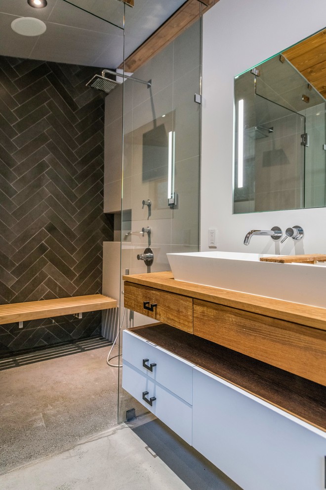 This is an example of a large contemporary ensuite bathroom in Los Angeles with flat-panel cabinets, white cabinets, an alcove shower, black tiles, cement tiles, white walls, concrete flooring, a trough sink, wooden worktops, grey floors, a hinged door and brown worktops.