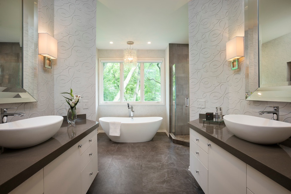 This is an example of a medium sized contemporary ensuite bathroom in Minneapolis with a vessel sink, flat-panel cabinets, white cabinets, solid surface worktops, a freestanding bath, a corner shower, a one-piece toilet, brown tiles, porcelain tiles, white walls and porcelain flooring.