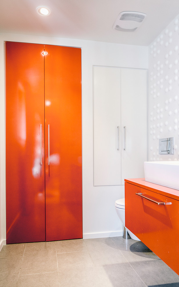 Foto de cuarto de baño moderno pequeño con armarios con paneles lisos, puertas de armario naranjas, paredes blancas, aseo y ducha y lavabo sobreencimera