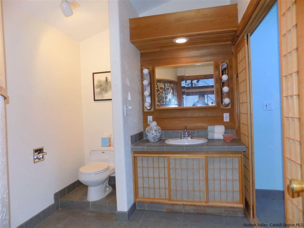 На фото: главная ванная комната среднего размера в восточном стиле с унитазом-моноблоком, серой плиткой, белыми стенами, полом из сланца, накладной раковиной и столешницей из талькохлорита