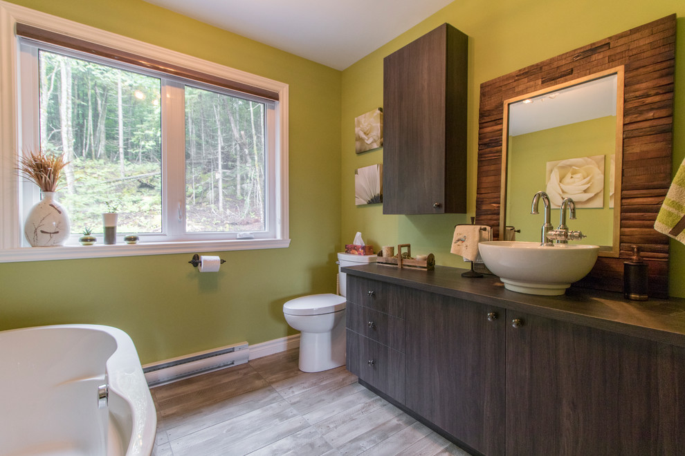 Foto de cuarto de baño moderno con armarios con paneles lisos, puertas de armario marrones, paredes verdes, suelo marrón y bañera exenta