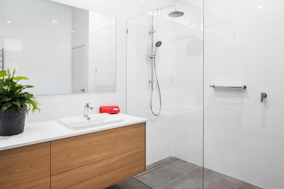 Imagen de cuarto de baño moderno con armarios con paneles lisos, puertas de armario de madera oscura, baldosas y/o azulejos blancos, lavabo encastrado, encimera de cuarzo compacto y encimeras blancas