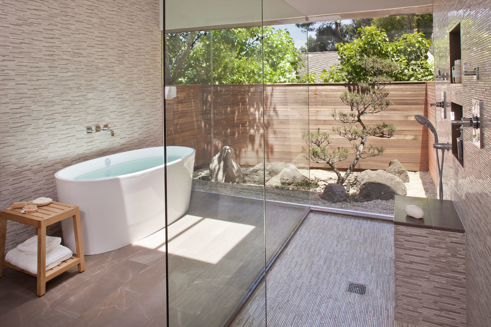 Modelo de cuarto de baño actual con bañera exenta, ducha abierta, baldosas y/o azulejos grises, azulejos en listel y ducha abierta