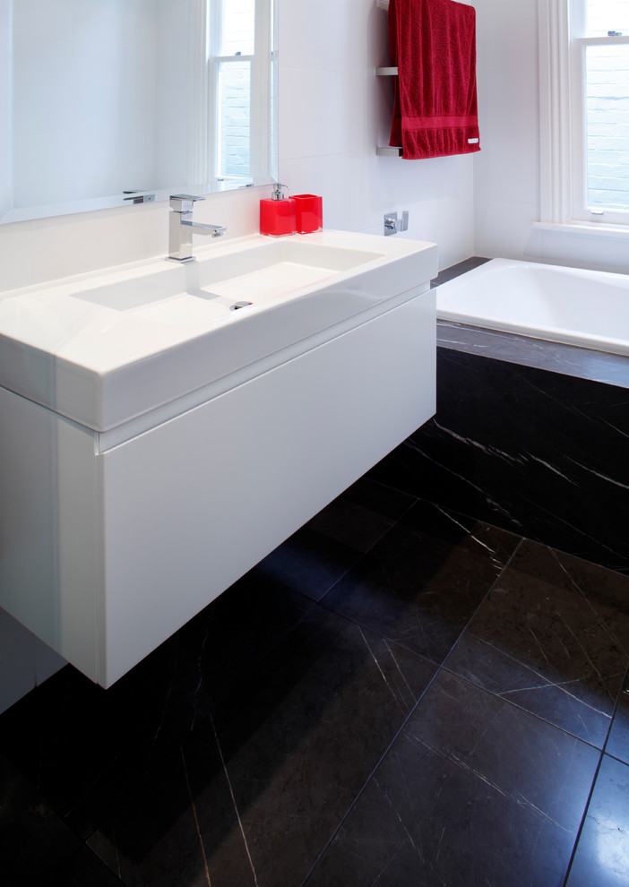 Пример оригинального дизайна: главная ванная комната в стиле модернизм с монолитной раковиной, плоскими фасадами, белыми фасадами, столешницей из искусственного камня, накладной ванной, белой плиткой, керамической плиткой, белыми стенами и полом из керамической плитки