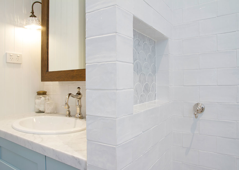 Bild på ett mellanstort lantligt badrum, med luckor med infälld panel, en öppen dusch, vit kakel, keramikplattor, vita väggar, marmorbänkskiva, en toalettstol med separat cisternkåpa, marmorgolv, ett undermonterad handfat och turkosa skåp