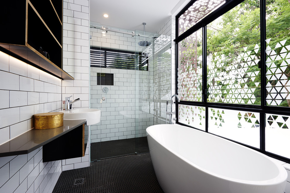 Inredning av ett modernt en-suite badrum, med ett fristående badkar, en kantlös dusch, vit kakel, tunnelbanekakel, vita väggar, ett integrerad handfat och dusch med skjutdörr