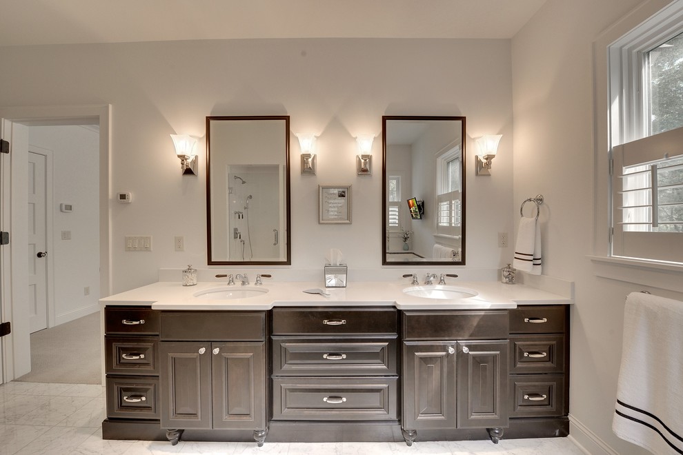 Inredning av ett klassiskt badrum, med ett undermonterad handfat, luckor med profilerade fronter, bruna skåp, flerfärgad kakel och vita väggar