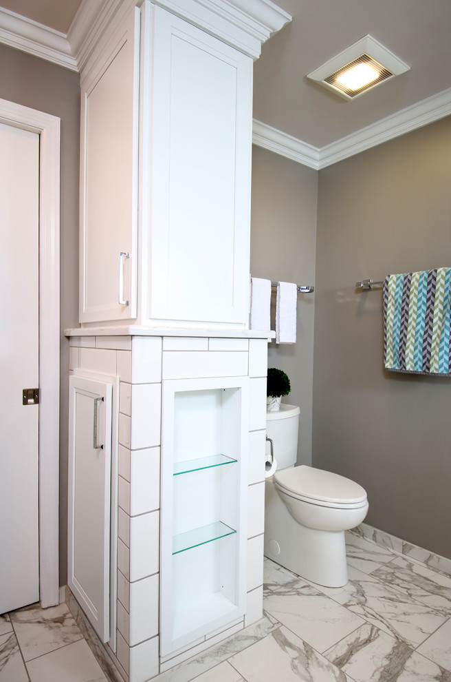 Mid-sized trendy master white tile and porcelain tile porcelain tile and multicolored floor bathroom photo in Columbus with flat-panel cabinets, white cabinets, a wall-mount toilet, brown walls, an undermount sink, marble countertops, a hinged shower door and multicolored countertops