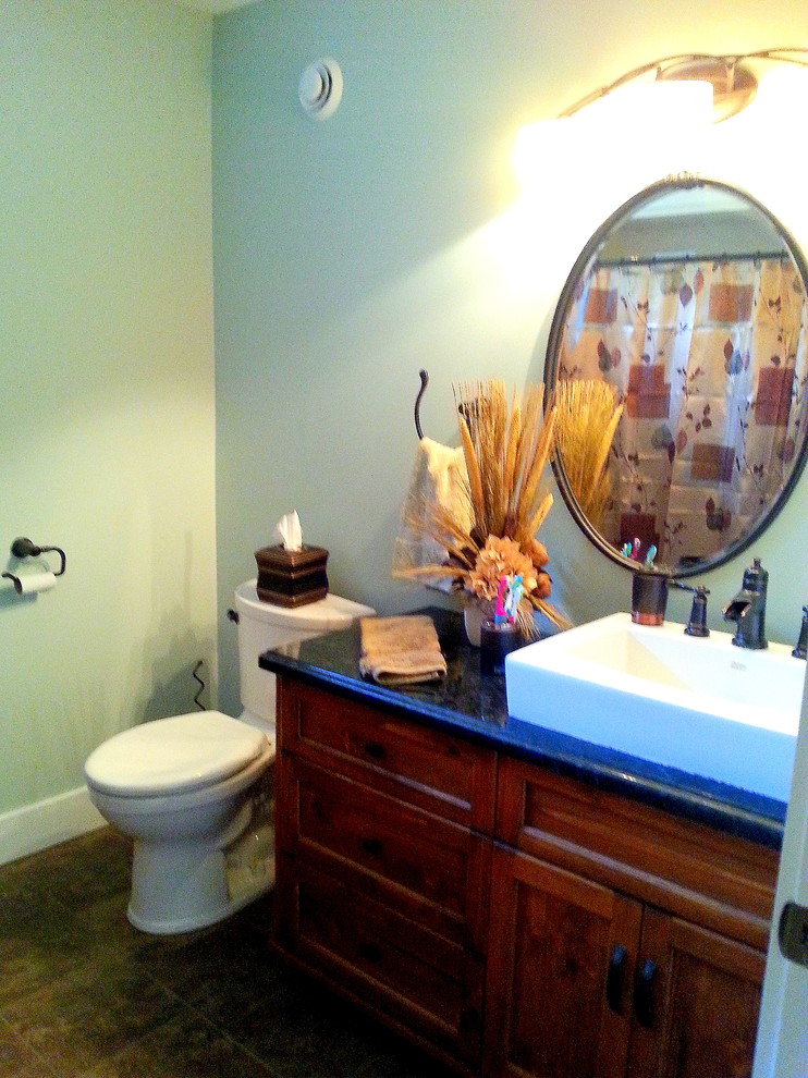 Bild på ett mellanstort rustikt badrum, med ett fristående handfat, möbel-liknande, skåp i mellenmörkt trä, granitbänkskiva, ett badkar i en alkov, en dusch i en alkov, en toalettstol med separat cisternkåpa, brun kakel, porslinskakel, gröna väggar och klinkergolv i porslin