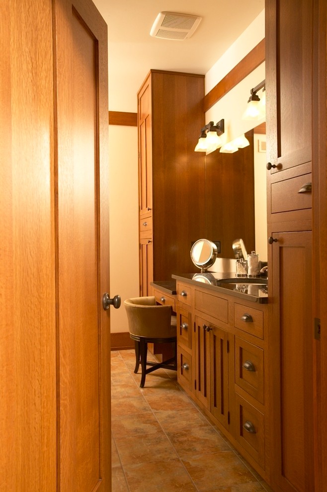 Imagen de cuarto de baño de estilo americano con lavabo bajoencimera, armarios con paneles lisos, puertas de armario de madera oscura y paredes beige