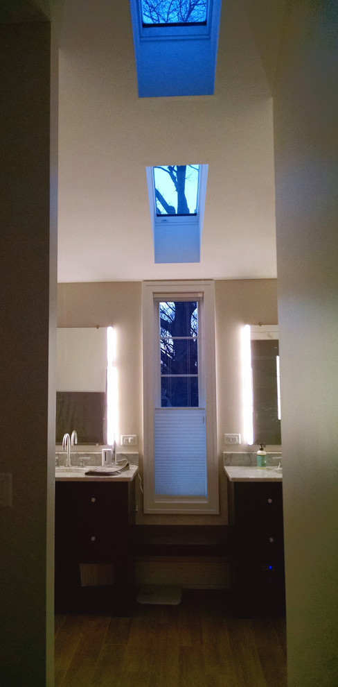 Modelo de cuarto de baño principal moderno grande con armarios con paneles lisos, puertas de armario de madera en tonos medios, paredes beige, suelo de madera en tonos medios, lavabo bajoencimera y encimera de cuarzo compacto