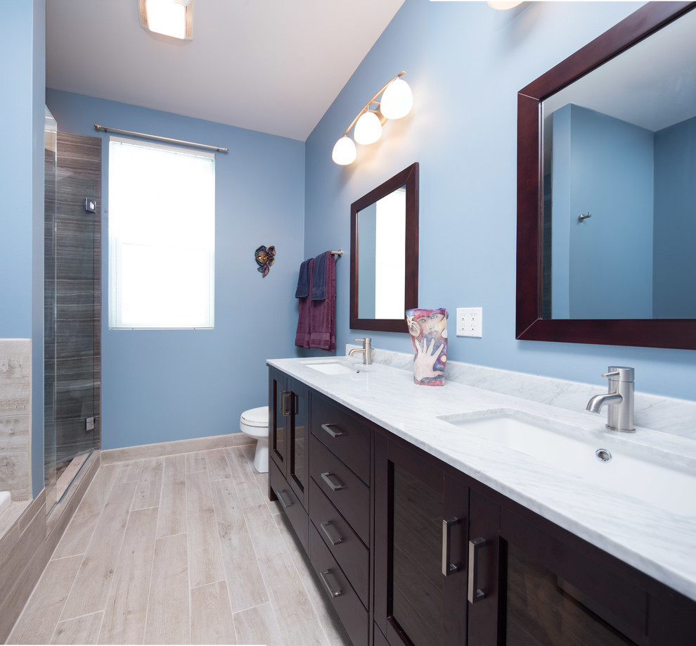 Bild på ett mellanstort funkis en-suite badrum, med skåp i shakerstil, skåp i mörkt trä, ett badkar i en alkov, en dusch i en alkov, en toalettstol med separat cisternkåpa, brun kakel, keramikplattor, blå väggar, klinkergolv i keramik, ett undermonterad handfat och marmorbänkskiva