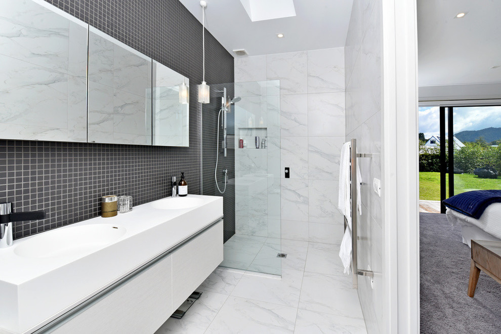 Modernes Badezimmer En Suite mit flächenbündigen Schrankfronten, weißen Schränken, bodengleicher Dusche, weißer Wandfarbe, Waschtischkonsole, weißem Boden, offener Dusche und weißer Waschtischplatte in Auckland