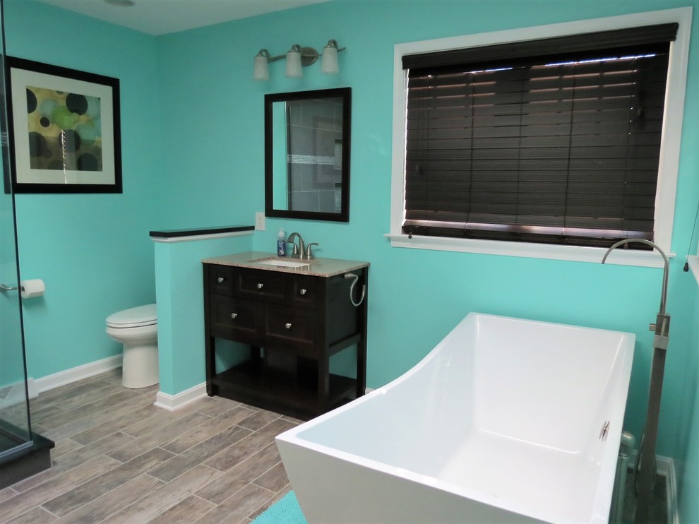 Bathroom - large transitional master gray tile and slate tile medium tone wood floor and gray floor bathroom idea in Baltimore with furniture-like cabinets, dark wood cabinets, a one-piece toilet, blue walls, an undermount sink, granite countertops and a hinged shower door