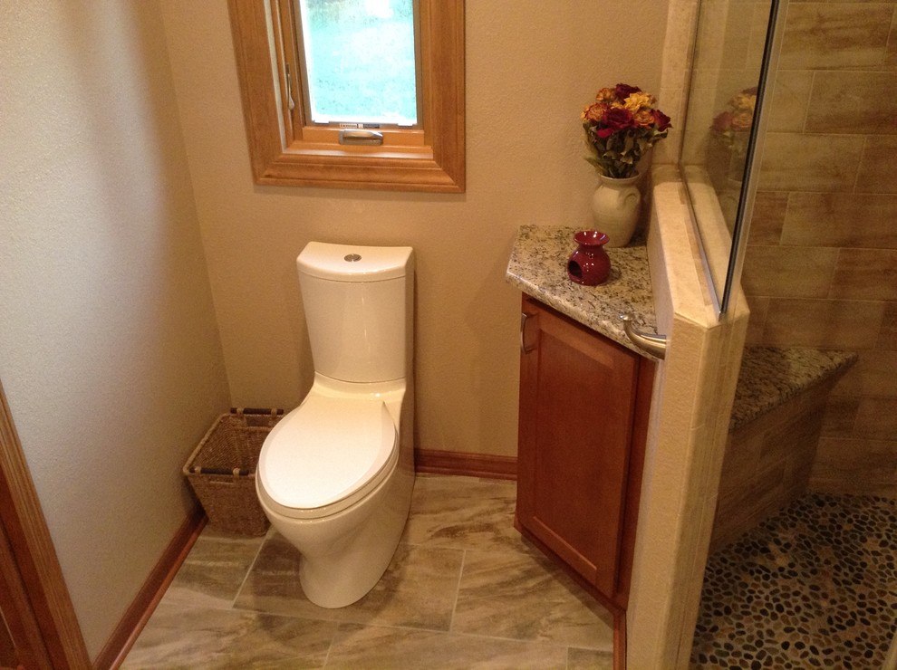 Photo of a medium sized modern cloakroom in Milwaukee with a submerged sink, shaker cabinets, medium wood cabinets, granite worktops, a two-piece toilet, brown tiles, ceramic tiles, beige walls and ceramic flooring.