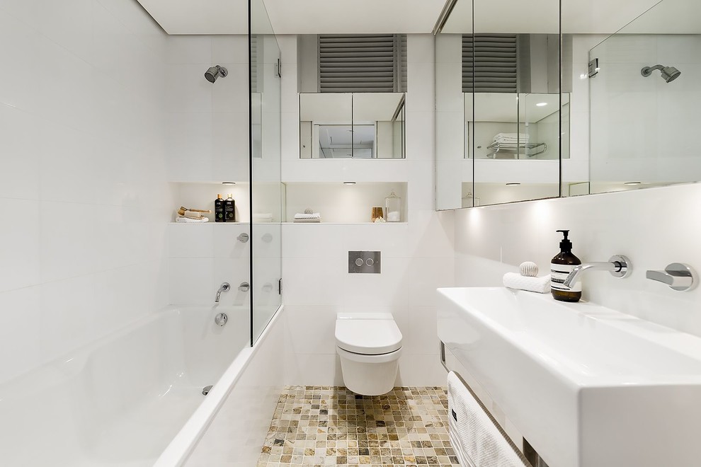 Modernes Duschbad mit Duschbadewanne, Wandtoilette, weißen Fliesen, weißer Wandfarbe, Wandwaschbecken, braunem Boden, offener Dusche und weißer Waschtischplatte in Sydney