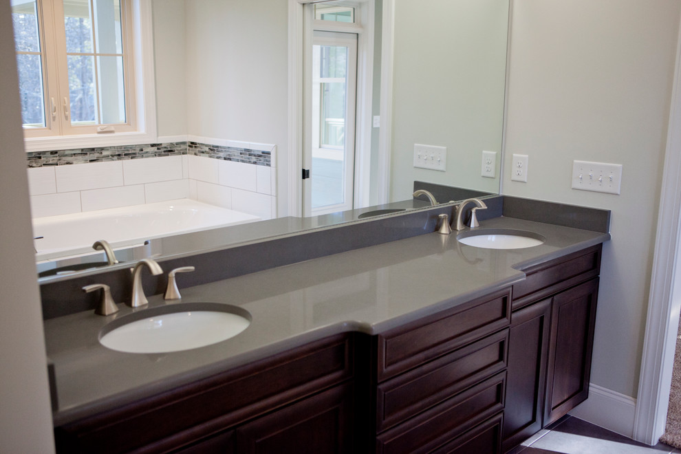 Photo of a large contemporary ensuite bathroom in Raleigh with recessed-panel cabinets, dark wood cabinets, granite worktops, a corner bath, a corner shower, grey tiles and glass tiles.