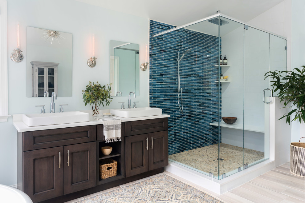 Идея дизайна: большая главная ванная комната в стиле неоклассика (современная классика) с фасадами в стиле шейкер, темными деревянными фасадами, отдельно стоящей ванной, угловым душем, раздельным унитазом, синей плиткой, стеклянной плиткой, синими стенами, полом из керамической плитки, настольной раковиной, столешницей из искусственного кварца, бежевым полом и душем с распашными дверями