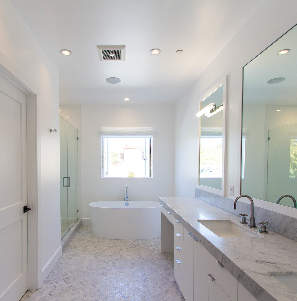 Modern inredning av ett stort en-suite badrum, med släta luckor, vita skåp, ett fristående badkar, en dusch i en alkov, vit kakel, stenkakel, vita väggar, marmorgolv, ett undermonterad handfat och marmorbänkskiva