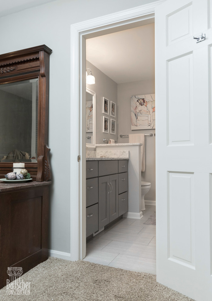 Inspiration for a small classic family bathroom in Cincinnati with flat-panel cabinets, grey cabinets, an alcove bath, a shower/bath combination, a one-piece toilet, white tiles, porcelain tiles, grey walls, porcelain flooring, a submerged sink, granite worktops, grey floors, a sliding door and grey worktops.
