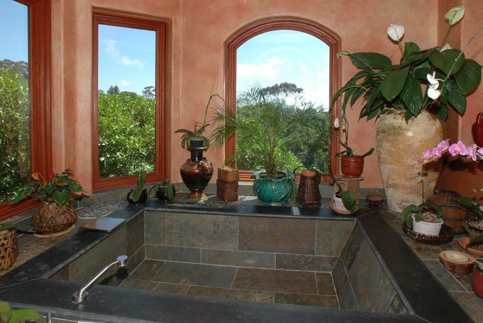 Photo of a large world-inspired ensuite bathroom in San Diego with a hot tub, grey tiles, stone tiles, pink walls, a one-piece toilet and an open shower.