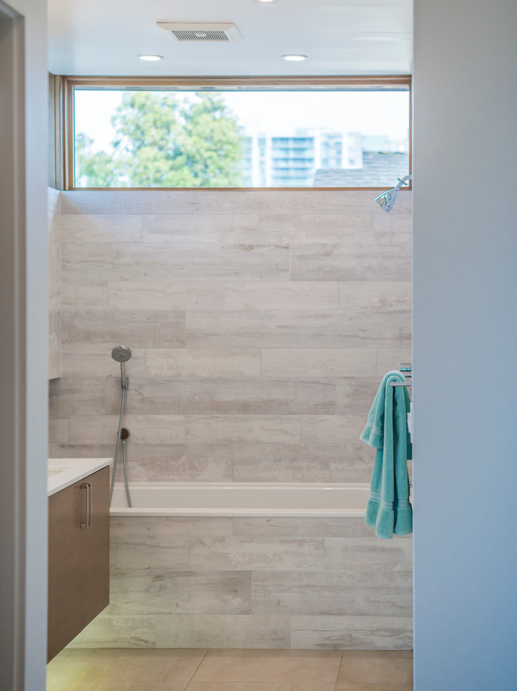 Example of a mid-sized trendy 3/4 gray tile and porcelain tile ceramic tile and beige floor bathroom design in Los Angeles with flat-panel cabinets, medium tone wood cabinets, a one-piece toilet, white walls, an undermount sink and solid surface countertops
