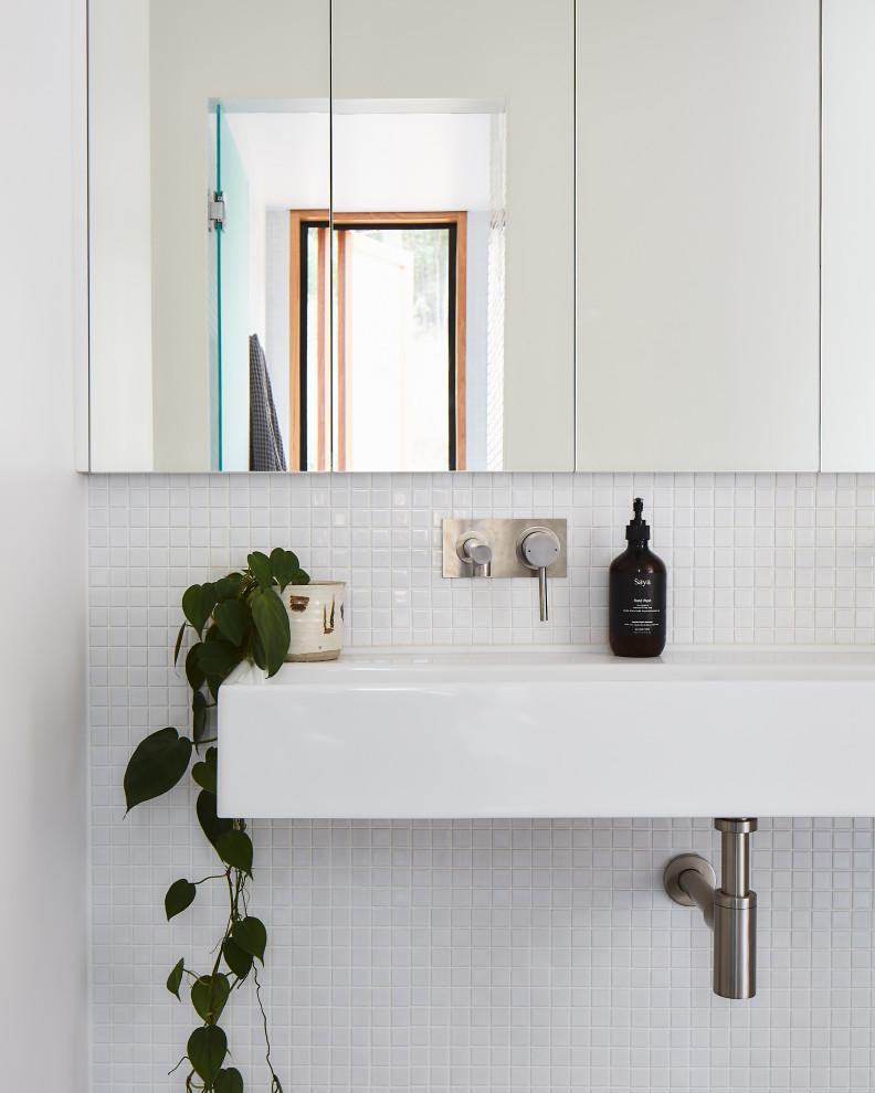 Immagine di una stanza da bagno moderna con piastrelle bianche, piastrelle a mosaico e lavabo sospeso