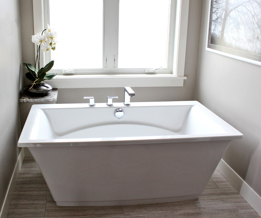 Amerikansk inredning av ett badrum, med ett fristående badkar, en öppen dusch, grå kakel, grå väggar och klinkergolv i keramik