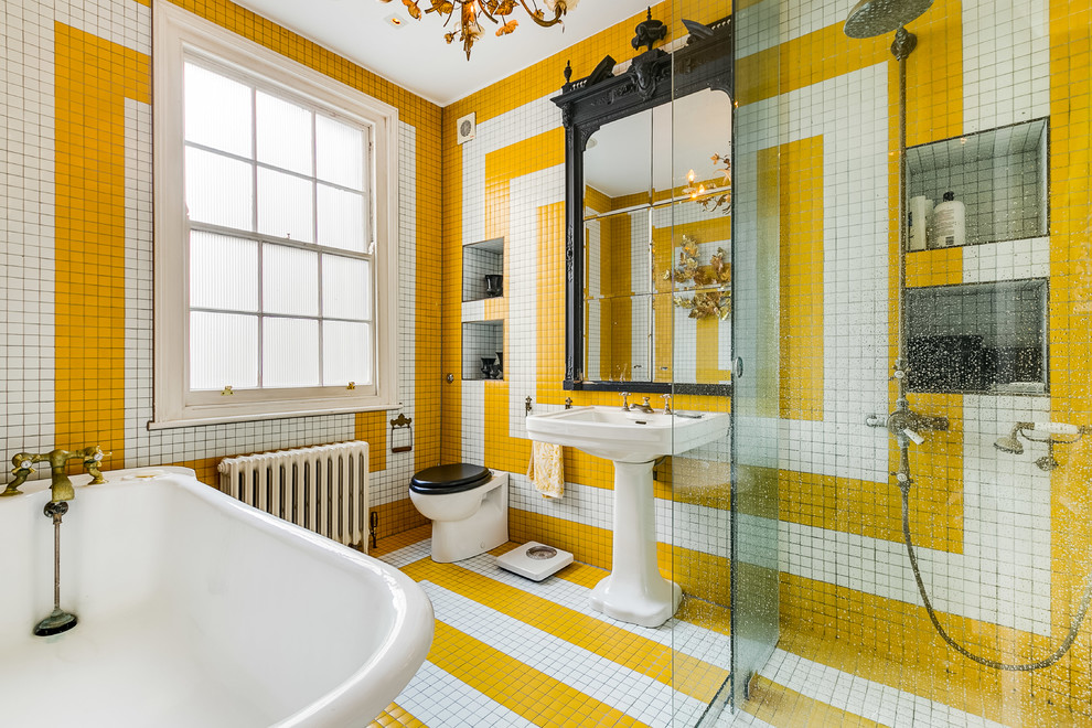 Inspiration for a bohemian ensuite wet room bathroom in London with a wall mounted toilet, multi-coloured tiles, white tiles, yellow tiles, multi-coloured walls, a pedestal sink, multi-coloured floors, a corner bath and ceramic tiles.