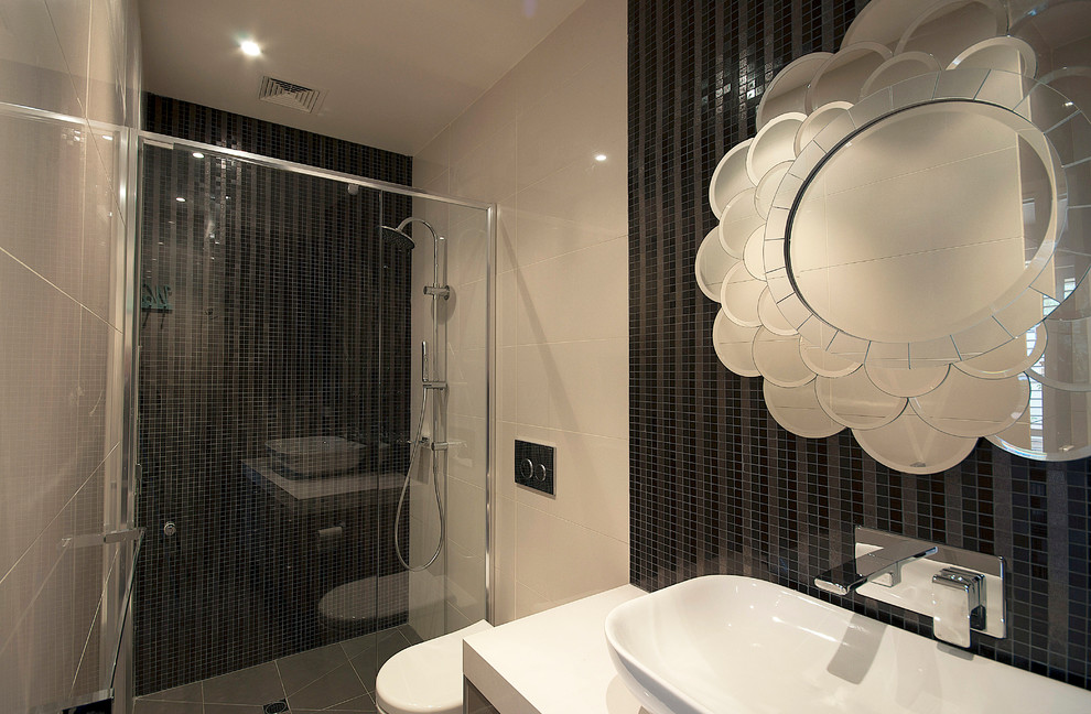 Design ideas for a medium sized contemporary shower room bathroom in Melbourne with flat-panel cabinets, grey cabinets, a built-in shower, a wall mounted toilet, black tiles, mosaic tiles, beige walls, porcelain flooring, a vessel sink, engineered stone worktops, grey floors and a hinged door.