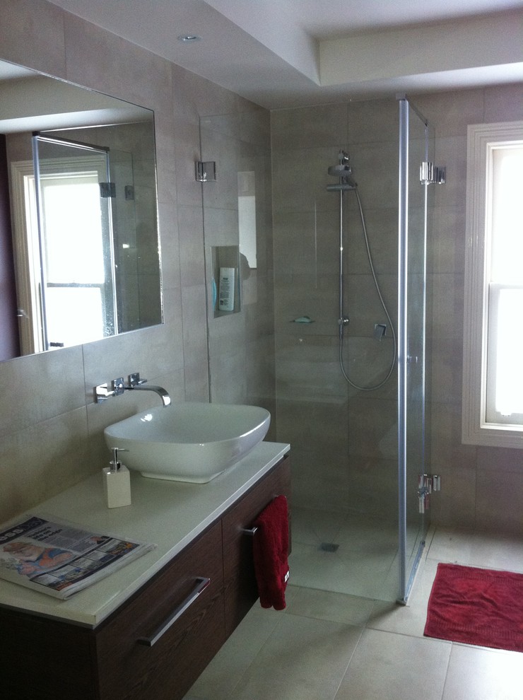 Aménagement d'une salle de bain principale contemporaine en bois brun de taille moyenne avec une vasque, un plan de toilette en quartz modifié, une douche d'angle, un carrelage gris, des carreaux de porcelaine, un mur gris et un sol en carrelage de porcelaine.