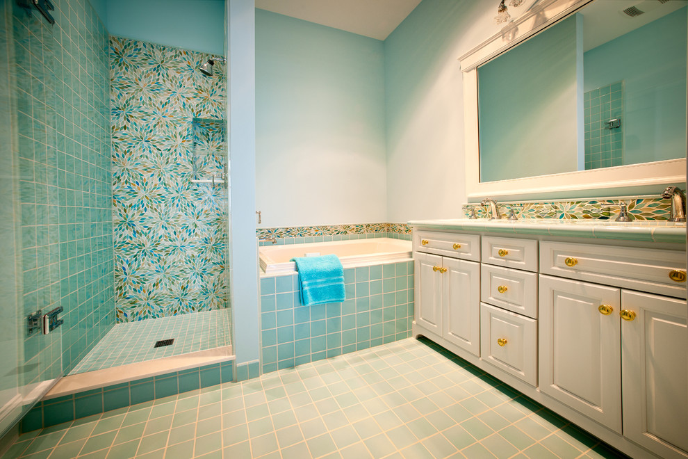 他の地域にある広いエクレクティックスタイルのおしゃれなマスターバスルーム (レイズドパネル扉のキャビネット、白いキャビネット、ドロップイン型浴槽、アルコーブ型シャワー、青いタイル、ガラスタイル、青い壁、セラミックタイルの床、アンダーカウンター洗面器、青い床、開き戸のシャワー) の写真