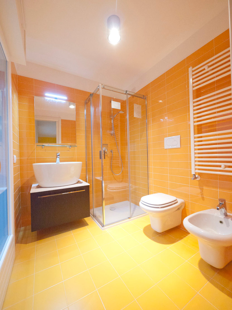 This is an example of a small modern bathroom in Milan with a console sink, flat-panel cabinets, brown cabinets, laminate worktops, a corner shower, a two-piece toilet, yellow tiles, orange tiles, porcelain tiles, yellow walls and porcelain flooring.