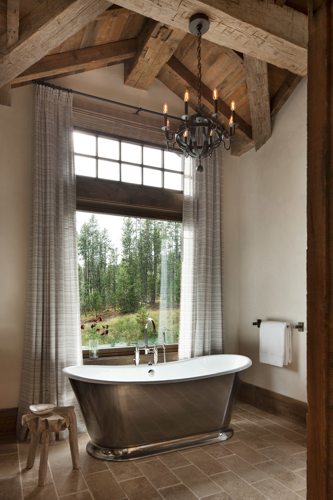 Expansive rustic ensuite bathroom in Other with a freestanding bath, white walls, porcelain flooring and brown floors.