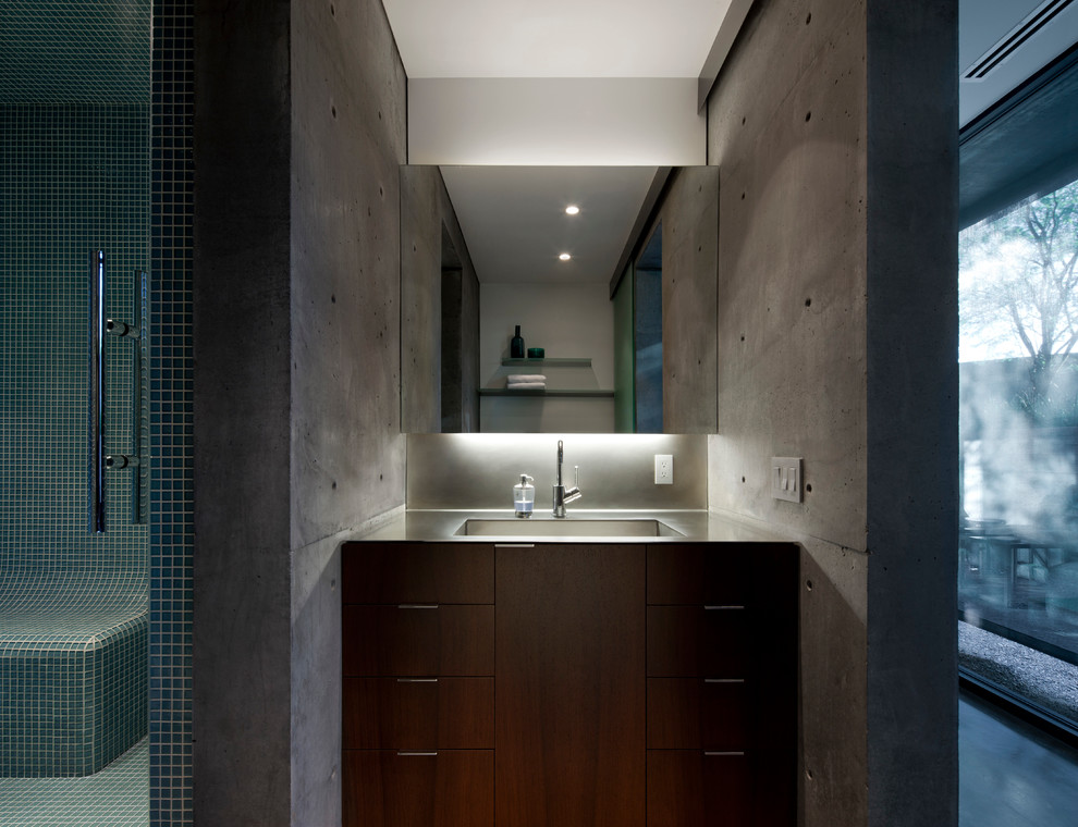 Пример оригинального дизайна: ванная комната среднего размера в стиле модернизм с плоскими фасадами, темными деревянными фасадами, открытым душем, инсталляцией, синей плиткой, стеклянной плиткой, белыми стенами, бетонным полом, душевой кабиной, врезной раковиной и столешницей из нержавеющей стали