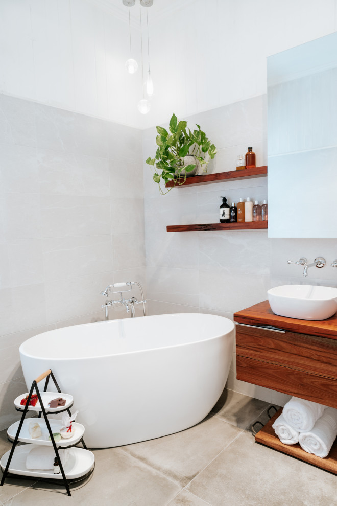 Immagine di una stanza da bagno padronale industriale con ante in legno scuro, vasca freestanding, piastrelle grigie, piastrelle in ceramica, pavimento in cementine e top in legno