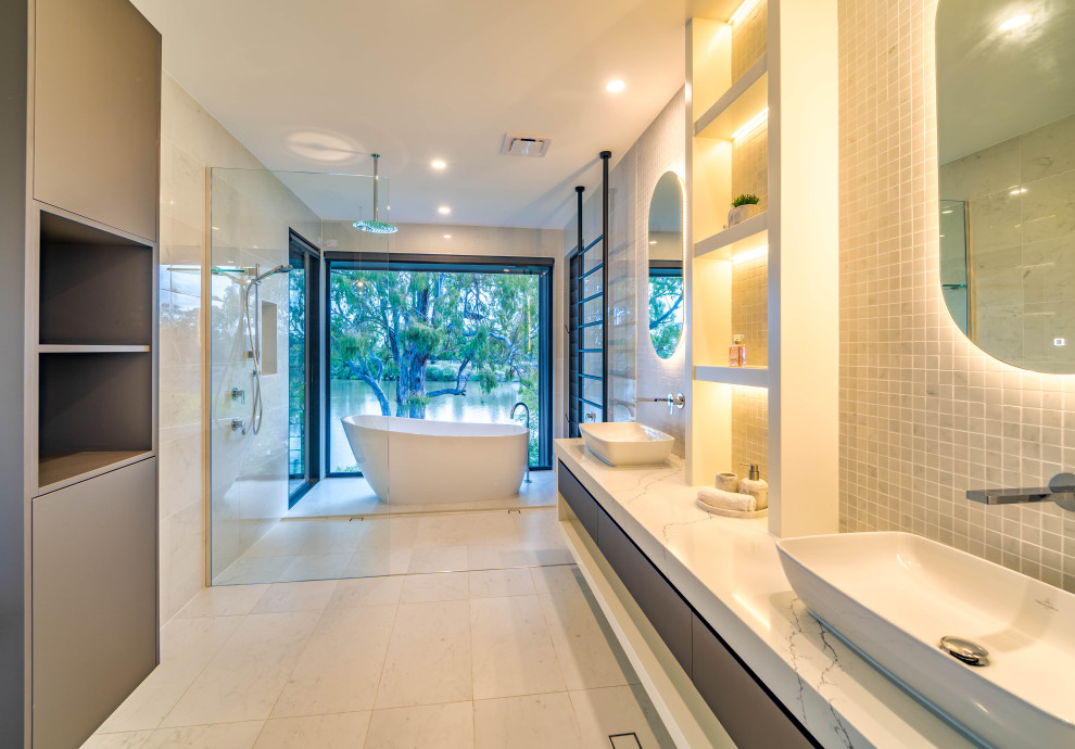 Идея дизайна: ванная комната в современном стиле с плоскими фасадами, серыми фасадами, отдельно стоящей ванной, душевой комнатой, серой плиткой, плиткой мозаикой, белыми стенами, настольной раковиной, белой столешницей, нишей, тумбой под две раковины и подвесной тумбой