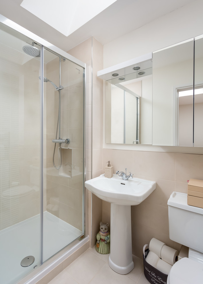 Inspiration for a medium sized contemporary ensuite bathroom in Gloucestershire with glass-front cabinets, white cabinets, a corner shower, a one-piece toilet, beige tiles, beige walls, a pedestal sink, beige floors, a hinged door and white worktops.
