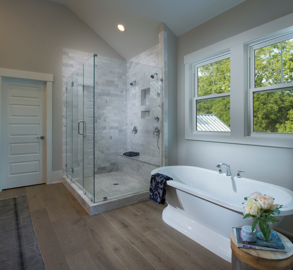 Ejemplo de cuarto de baño principal de estilo de casa de campo grande con bañera exenta, ducha esquinera, baldosas y/o azulejos grises, baldosas y/o azulejos de cemento, paredes grises y suelo de madera clara