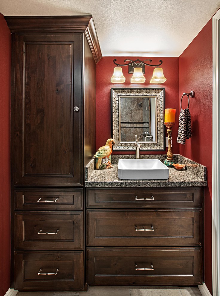 Modelo de cuarto de baño tradicional pequeño con lavabo sobreencimera, armarios con paneles empotrados, puertas de armario de madera en tonos medios, encimera de granito, baldosas y/o azulejos beige, baldosas y/o azulejos de porcelana, paredes rojas y aseo y ducha