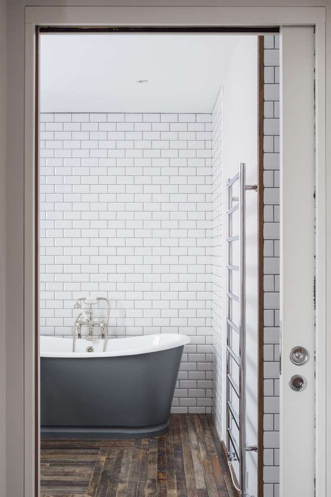 Bild på ett stort industriellt en-suite badrum, med ett fristående badkar, vit kakel, keramikplattor, vita väggar och mörkt trägolv