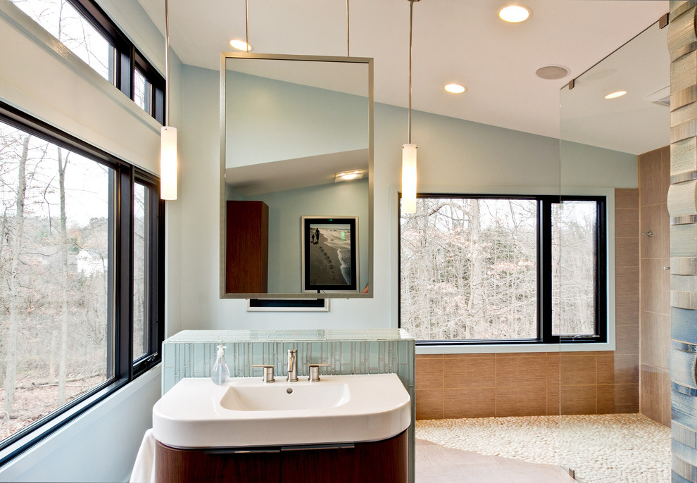 Modelo de cuarto de baño principal moderno grande con armarios con paneles lisos, puertas de armario de madera en tonos medios, ducha abierta, paredes grises, suelo de baldosas de porcelana, lavabo integrado y encimera de acrílico