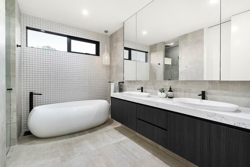 Modelo de cuarto de baño contemporáneo con armarios con paneles lisos, puertas de armario negras, bañera exenta y paredes grises