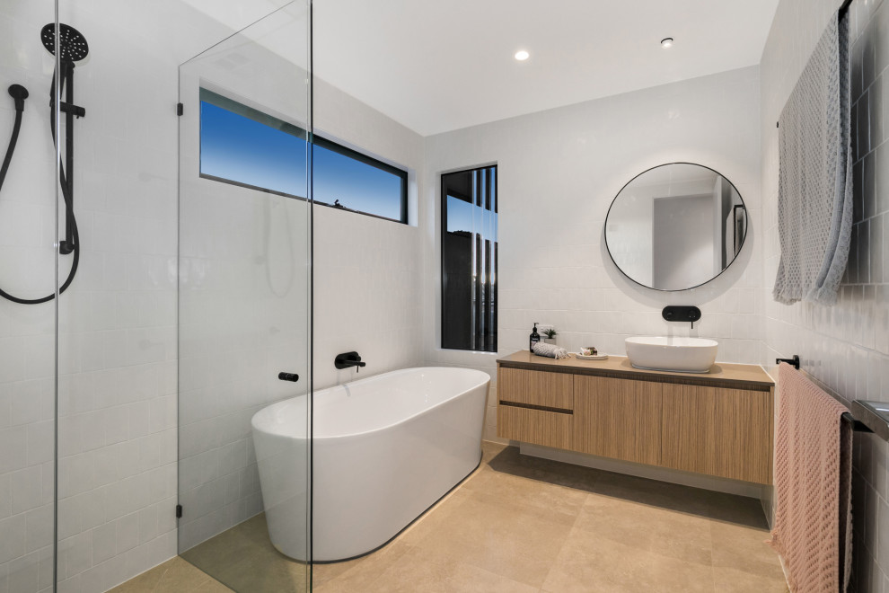 Réalisation d'une salle de bain design en bois brun avec un placard à porte plane, une baignoire indépendante, un carrelage blanc, une vasque, un sol marron et un plan de toilette marron.