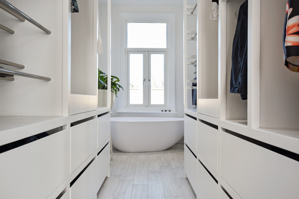 Diseño de cuarto de baño principal moderno de tamaño medio con bañera exenta, paredes blancas, imitación a madera y vestidor
