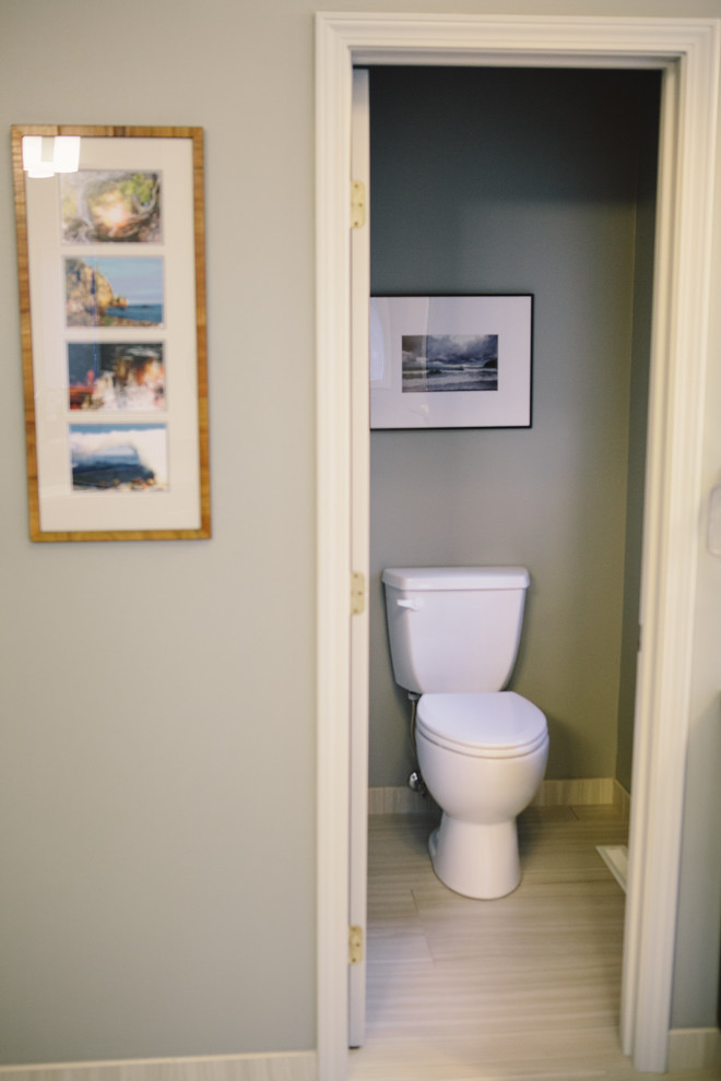 Exempel på ett stort modernt toalett, med ett undermonterad handfat, luckor med infälld panel, skåp i mörkt trä, bänkskiva i akrylsten, en toalettstol med separat cisternkåpa, beige kakel, porslinskakel, grå väggar och klinkergolv i porslin