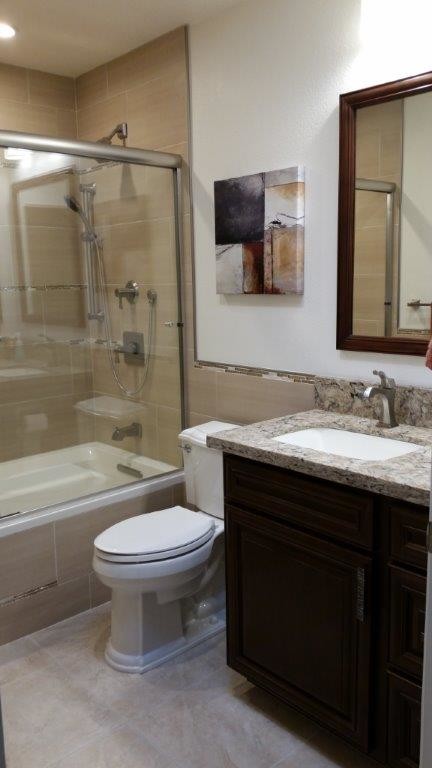 На фото: маленькая ванная комната в современном стиле с фасадами с утопленной филенкой, темными деревянными фасадами, полновстраиваемой ванной, душем над ванной, унитазом-моноблоком, бежевой плиткой, керамогранитной плиткой, белыми стенами, полом из керамической плитки, душевой кабиной, врезной раковиной и столешницей из кварцита для на участке и в саду с
