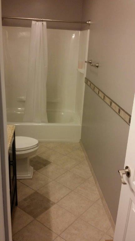Cette photo montre une petite salle de bain chic en bois foncé avec un lavabo encastré, un placard à porte shaker, un plan de toilette en granite, une baignoire en alcôve, un combiné douche/baignoire, WC séparés, un carrelage gris, des carreaux de porcelaine, un mur gris et un sol en carrelage de porcelaine.
